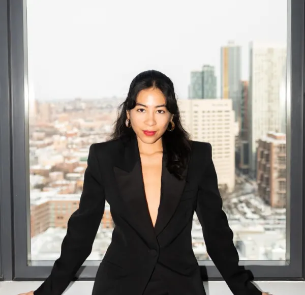 woman, long dark hair, professional stylized headshot, black blazer, sitting in front of window