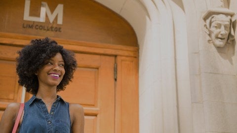 A woman standing at the doors of LIM College.