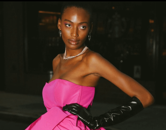 Model in pink dress with black gloves.