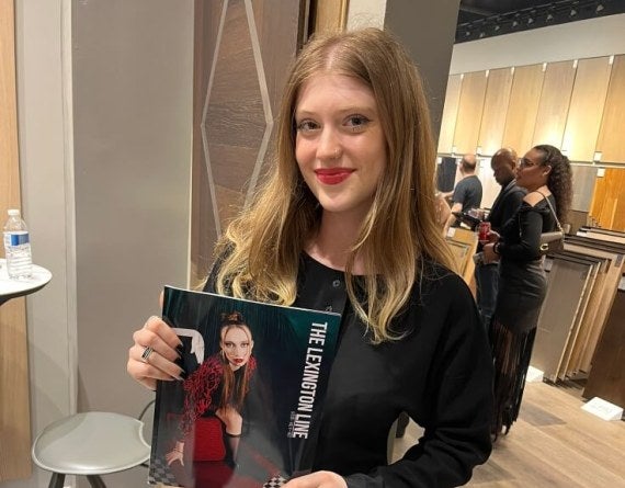young woman, long red hair, holds copy of Lexington Line magazine