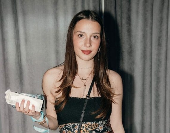 young woman, long brown hair, nicely dressed, black dress, stage curtain behind her