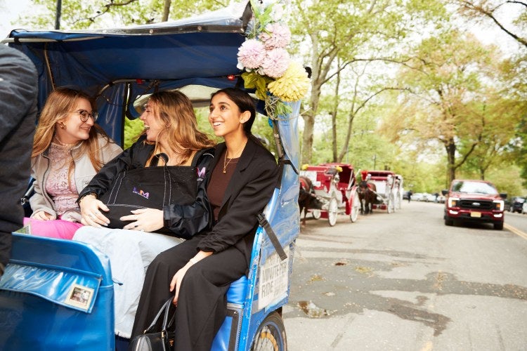 three female students in a horse-drawn carriage in Central Park