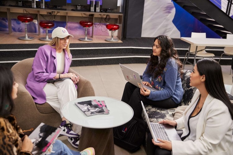 four students sitting around a coffee table in a lounge