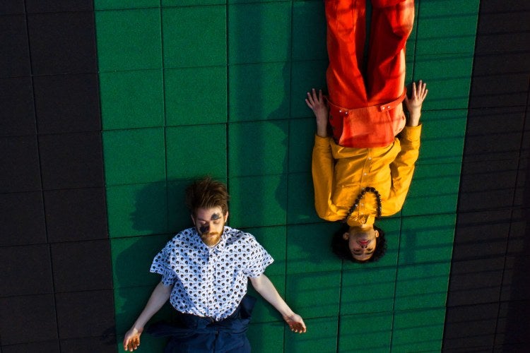photo from above of two people laying on a green floor