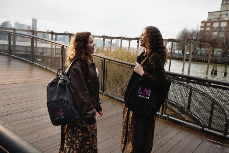 Two LIM students stand on the boardwalk at South Cove Park, near Battery Park in New York