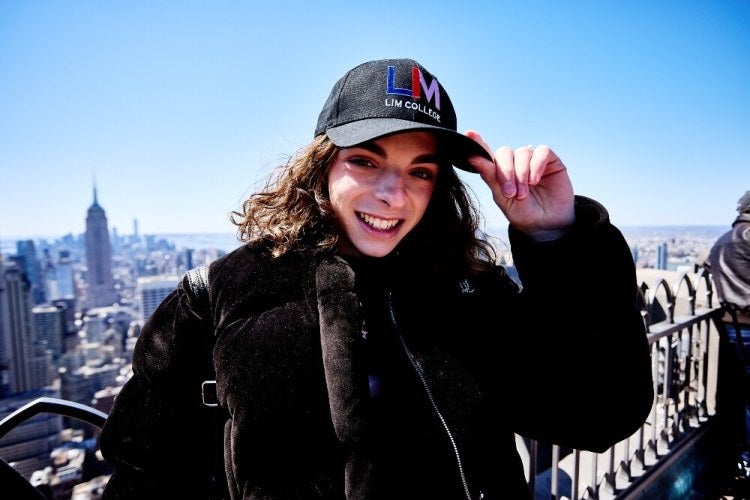 LIM student in branded baseball cap stands on the observatory level of 30 Rockefeller Plaza in New York