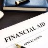 A financial aid application sits on a desk with a pen, calculator, and notebook nearby