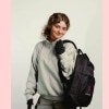 young woman, blond hair, LIM backpack, solid background