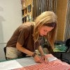 young woman, blond hair, brown shirt and headband, fabric swatches on swigning panels in background