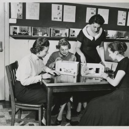 black and white photo 1950s students sitting around shawdow box displays
