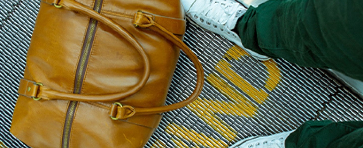 A suitcase at someone's feet at the airport.