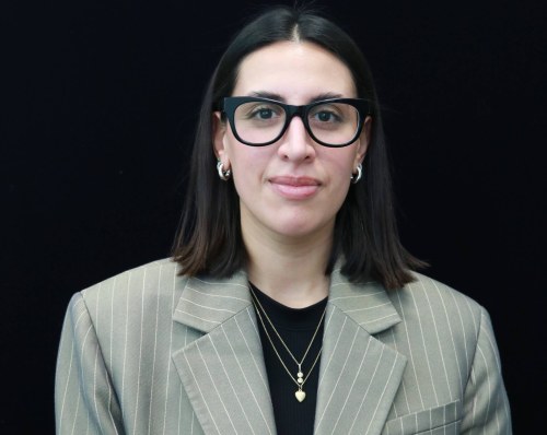 headshot of a woman wearing glasses in front of black background