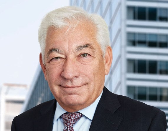 man standing in front of a building in a dark suit and tie